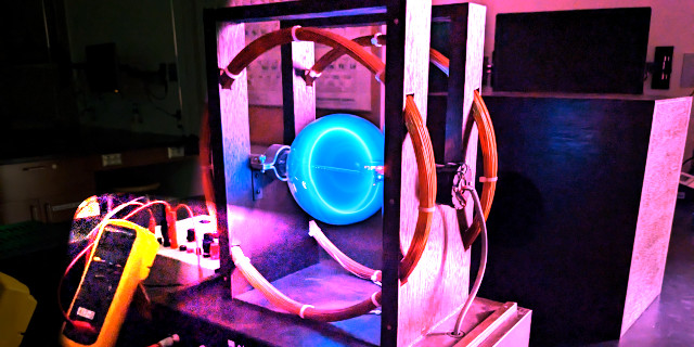 Apparatus showing the circular path of electrons in a magnetic field.