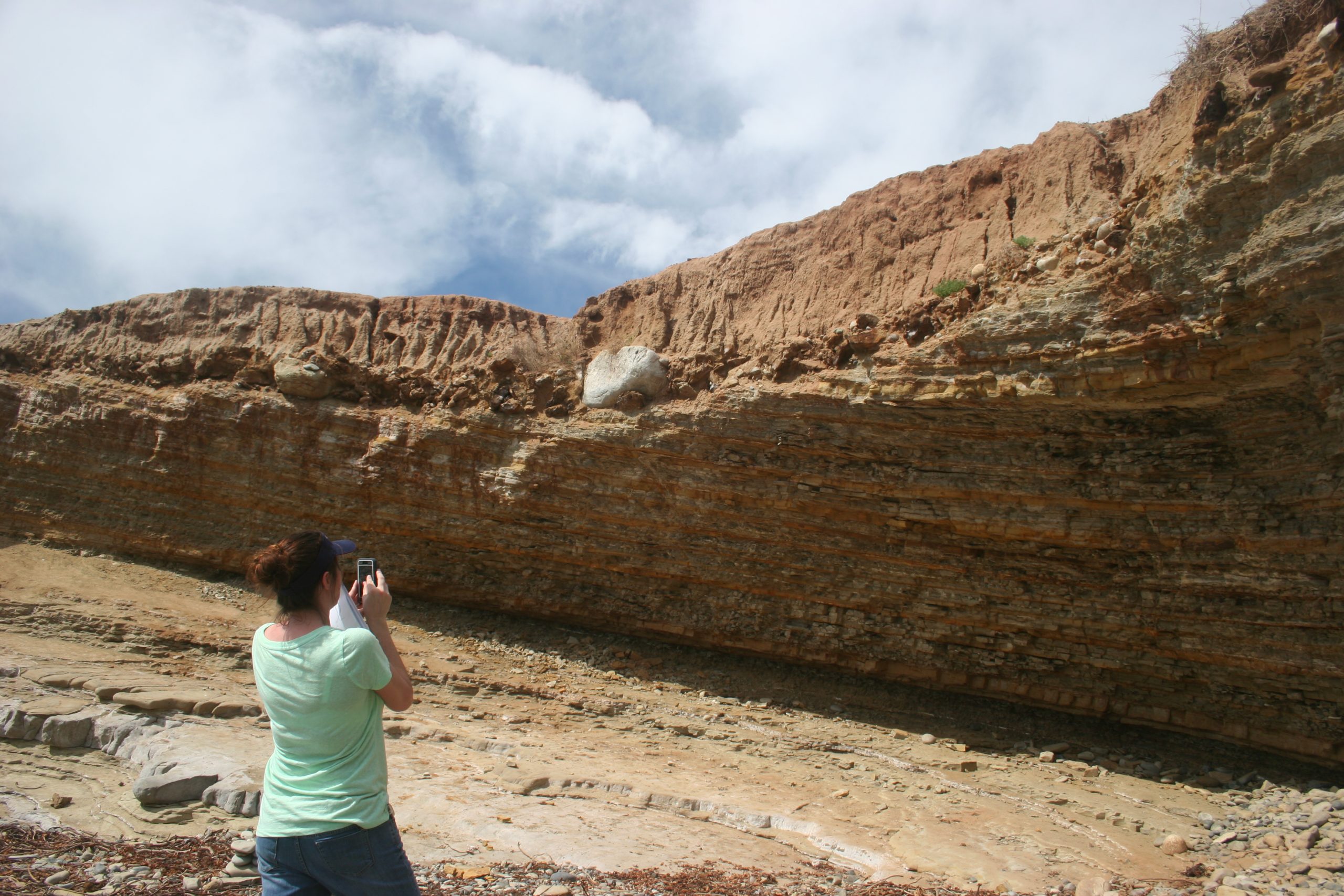 Student taking photo of sedimentary rock layers.